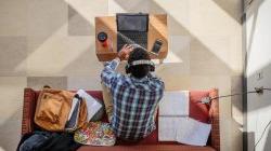 overhead photo of student on couch in a campus lounge using his laptop